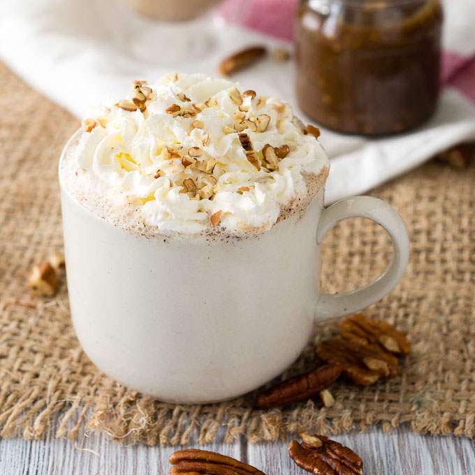 white cup with maple pecan latte, whipped cream and pecans