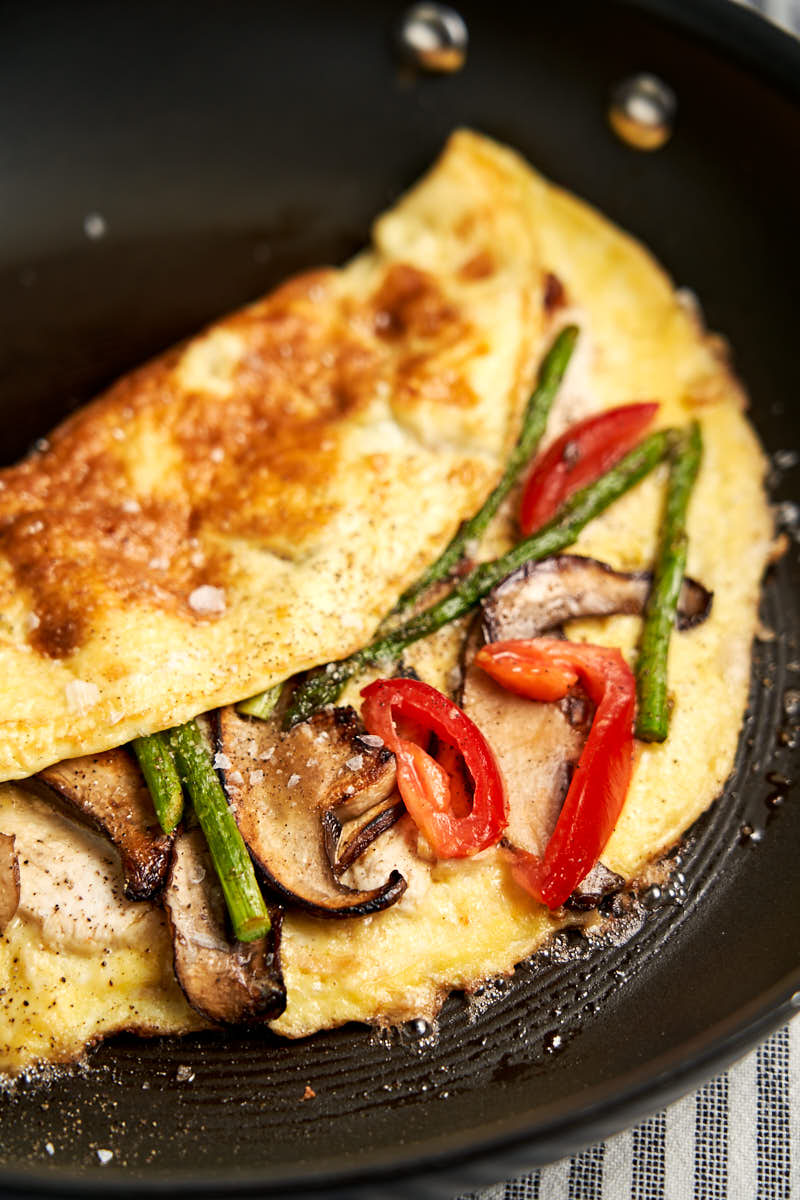 Leftover Chicken Cheese Omelette - folded in half on skillet showing mushrooms and asparagus and cheese | The Worktop