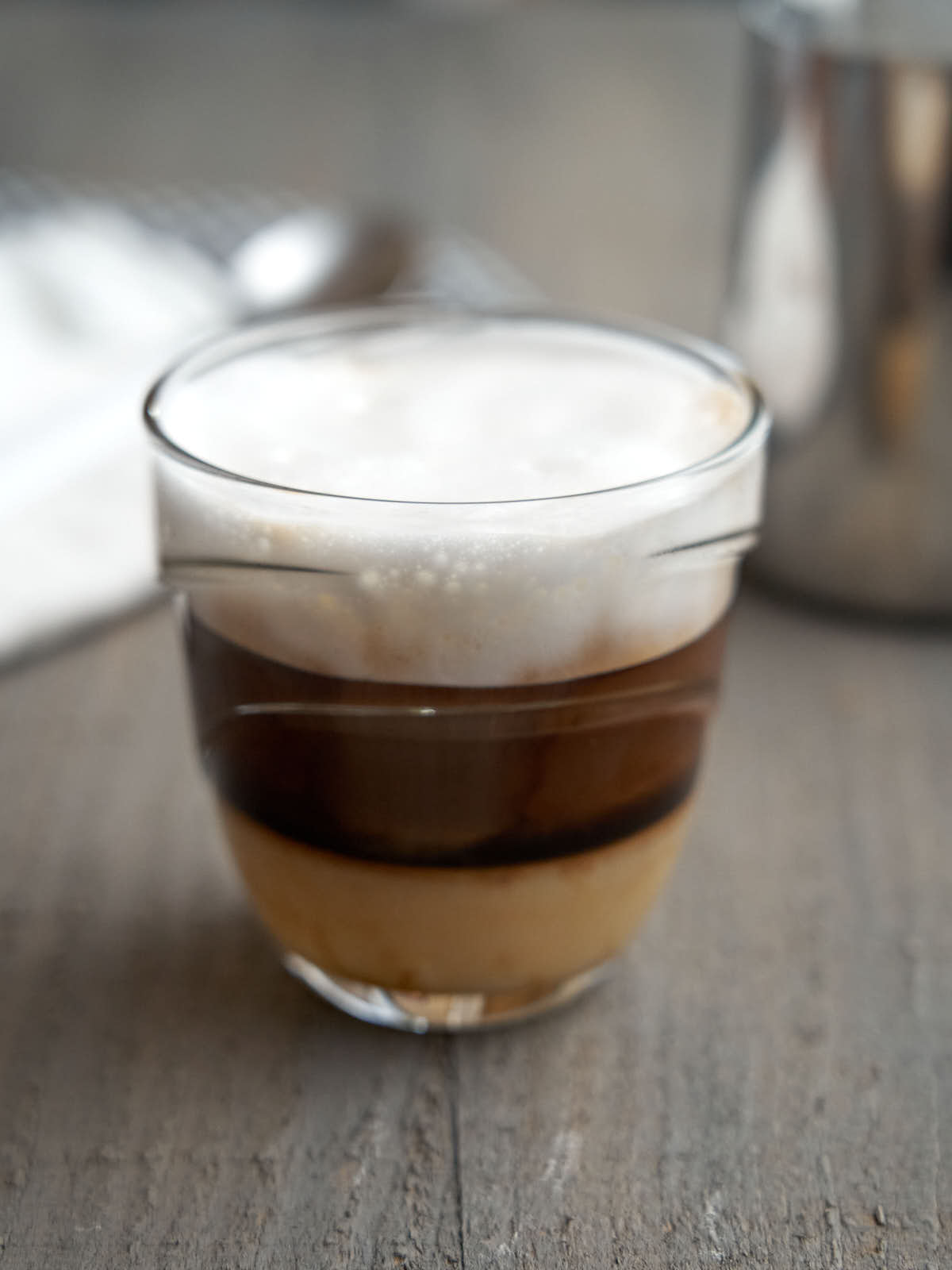 espresso layered with condensed milk and topped with froth in a class cup to be served
